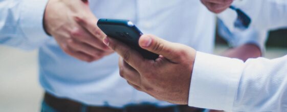 Office workers reviewing mobile device management on a cell phone