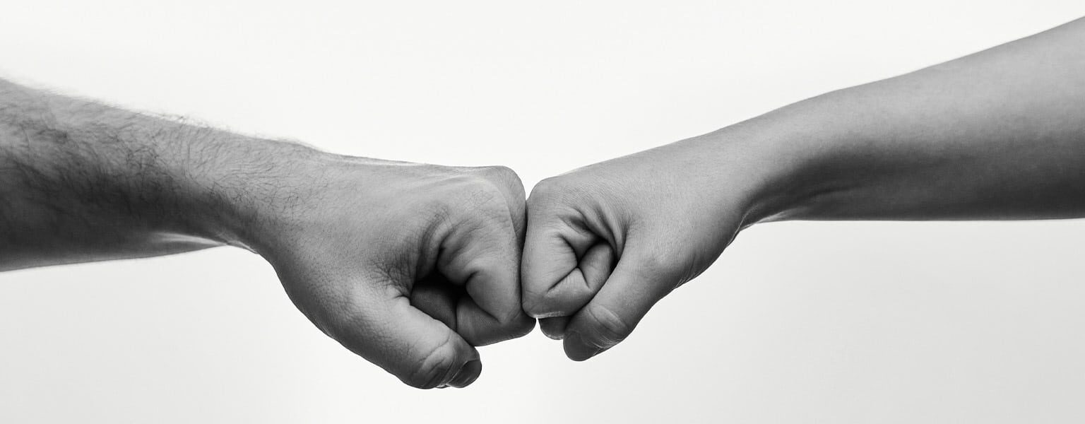 People giving each other knuckles to signify Outsourced IT Services VS In-House